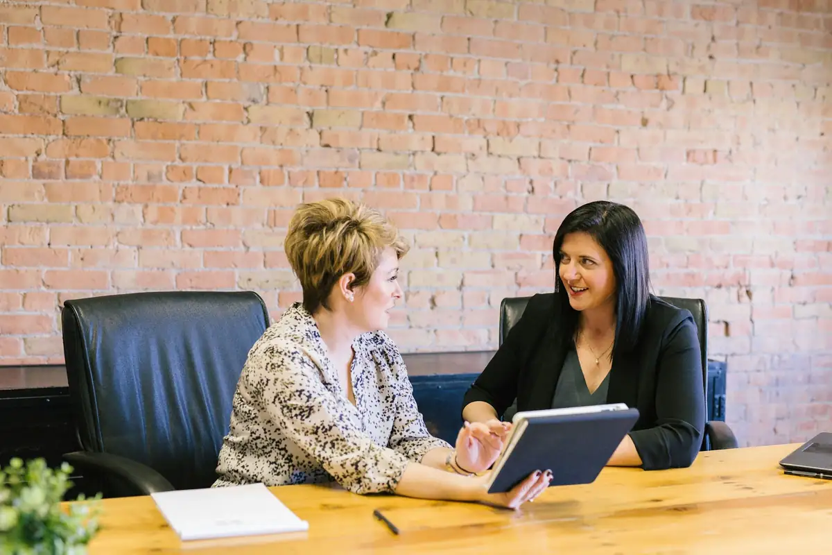 Deux femmes en rendez-vous de travail autour d'une tablette, à une table de bureau