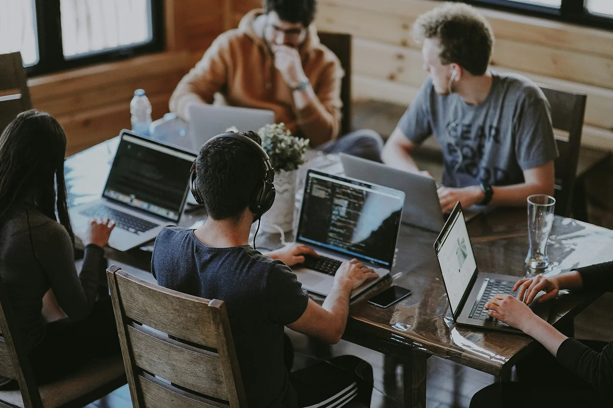 Équipe web qui travaille sur des ordinateurs portables autour d'une table